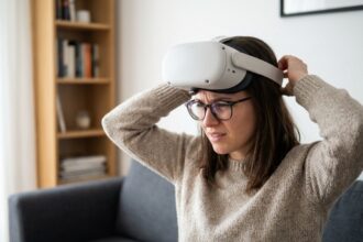 Femme portant des lunettes de vue sous un casque de réalité virtuelle, ajustant le dispositif avec une expression d'inconfort